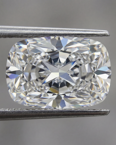 Cushion-shaped diamond held between tweezers against a blurred background